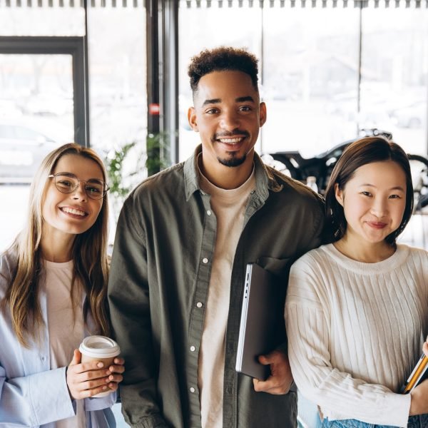 Diverse university students smiling and holding study materials in cafeteria